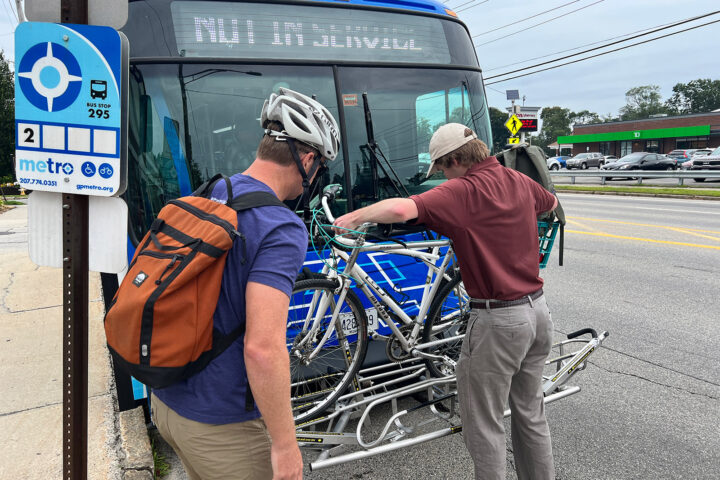 person putting bike on bus rack