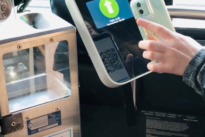 farebox and hand holding phone against barcode scanner