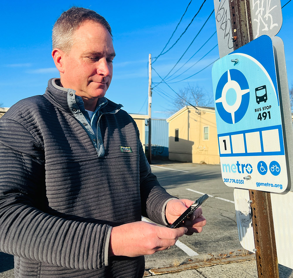 man standing next to bus stop sign